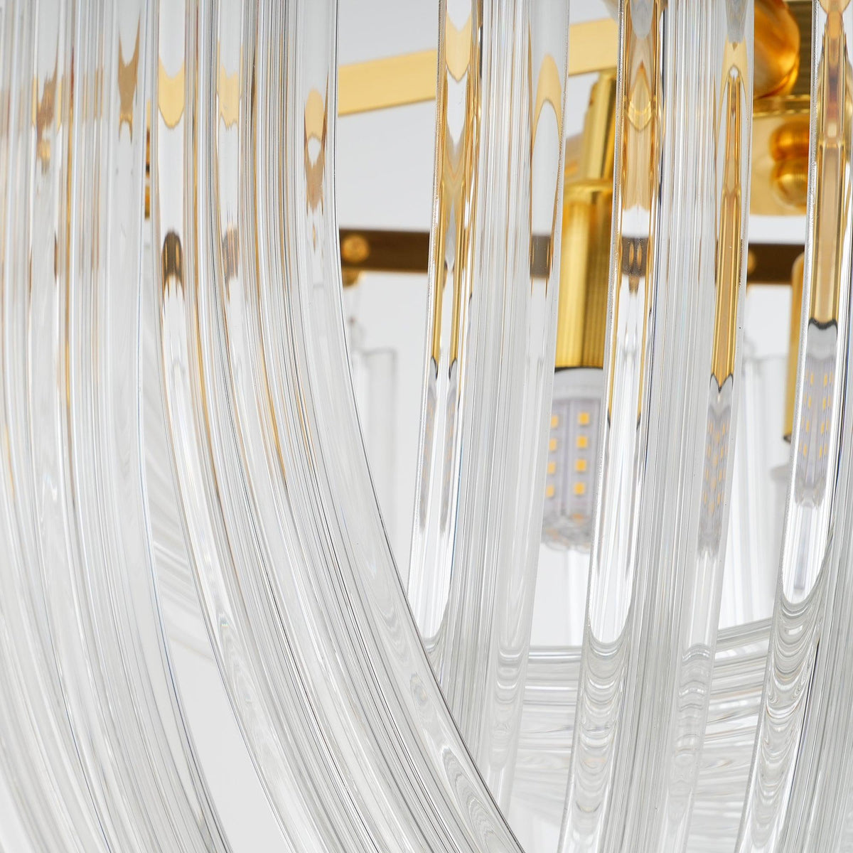 Close view of the clear glass rods curving around a gold lamp holder and a warm LED bulb inside this Clérachic chandelier.