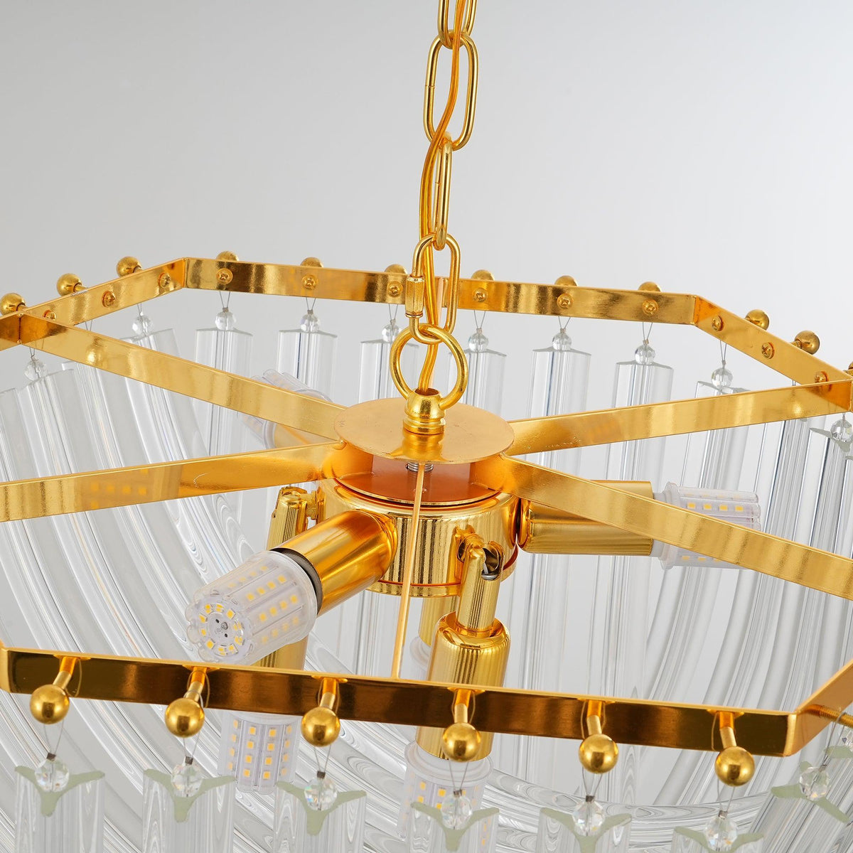 Close view of the hexagonal gold frame, central hub, LED bulbs and chain at the heart of this Clérachic chandelier.