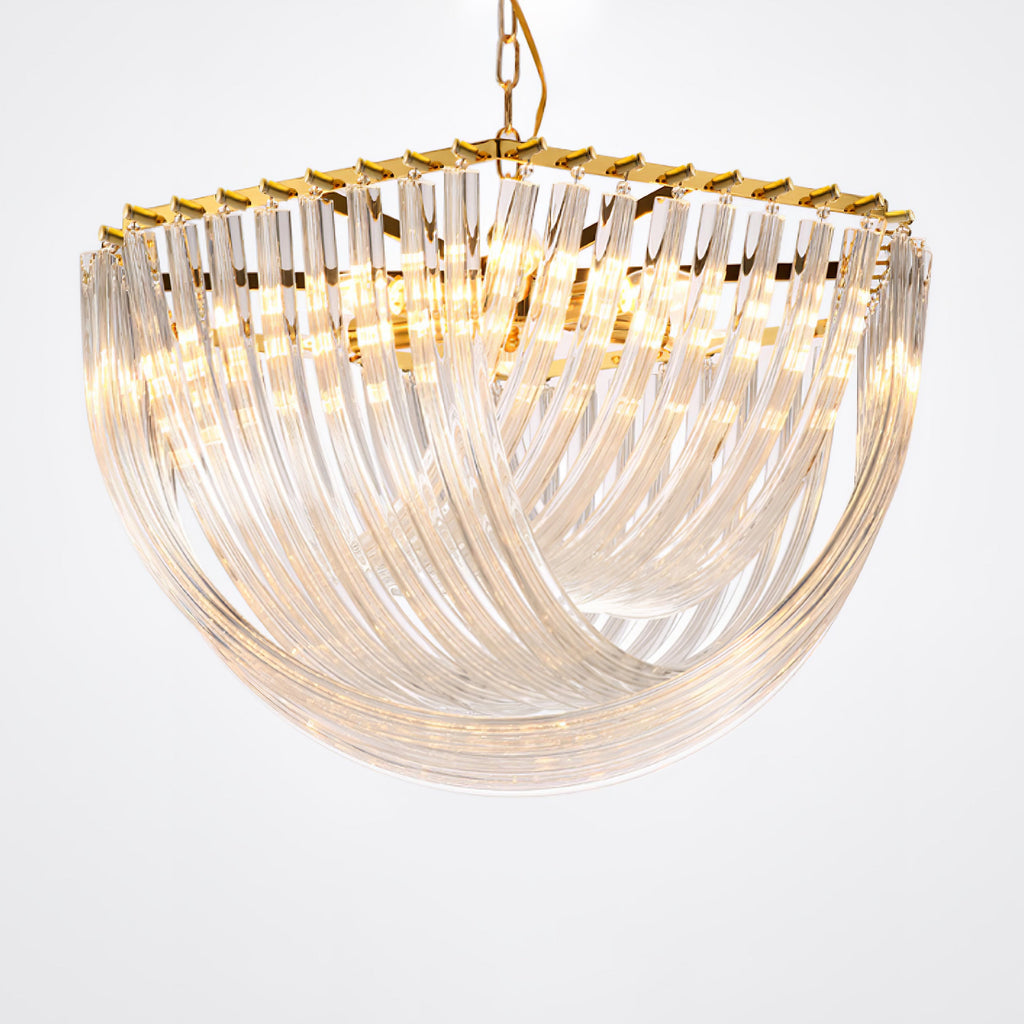 Close angled view of the curved clear glass rods and gold edge of this Clérachic chandelier, lit warmly on a pale backdrop.