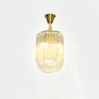 Narrow Clérachic looped-glass pendant on a brass canopy, lit with a warm glow against a pale backdrop.