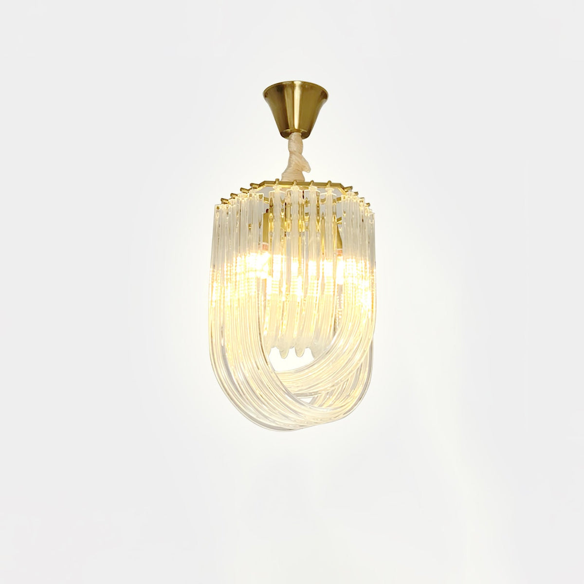 Narrow Clérachic looped-glass pendant on a brass canopy, lit with a warm glow against a pale backdrop.