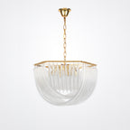 Unlit Clérachic chandelier on a gold chain, its pale clear glass rods looping beneath a square gold frame on a grey backdrop.