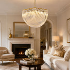 Large Clérachic glass chandelier above a cream living room with a marble fireplace, a gold-framed mirror and a pale sofa.