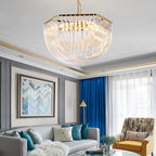 Clérachic chandelier with a hexagonal gold top above a grey sofa, blue curtains, a mustard patterned armchair and a chevron painting.