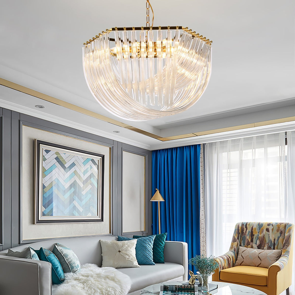 Clérachic chandelier with a hexagonal gold top above a grey sofa, blue curtains, a mustard patterned armchair and a chevron painting.