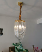 Narrow looped-glass Clérachic chandelier hung from a gold canopy on a twisted fabric cord, with a green bag on the floor below.