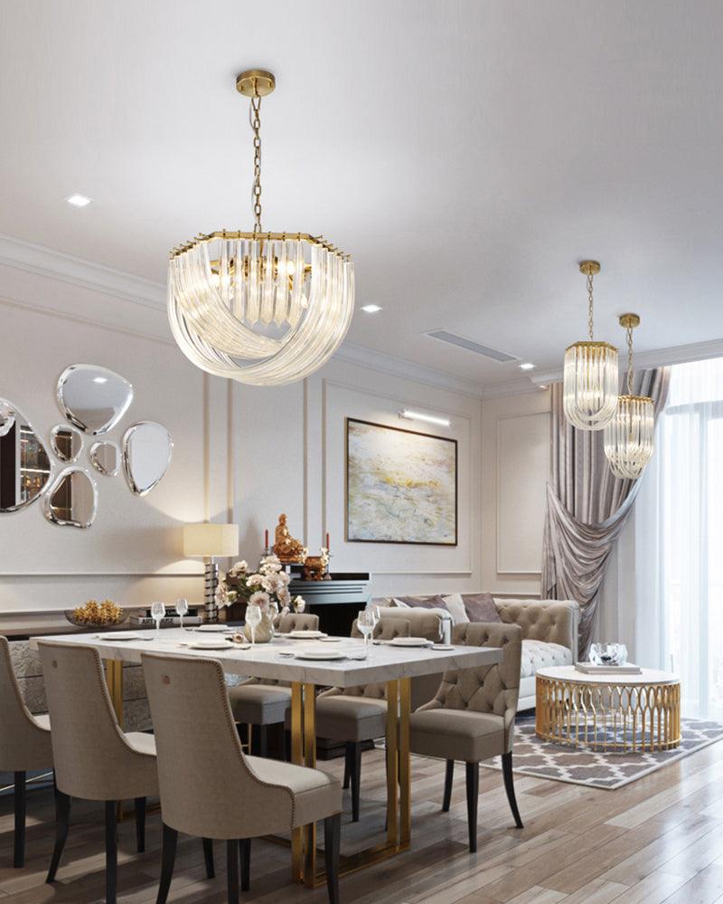 Clérachic chandelier above a white dining table with beige chairs, with two narrow pendants further back in the room.