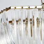 Close view of the gold frame, small gold balls and the hanging clear glass rods along the top of this Clérachic chandelier.