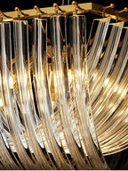 Close view of the clear glass rods and gold frame of this Clérachic chandelier, lit warmly from inside.