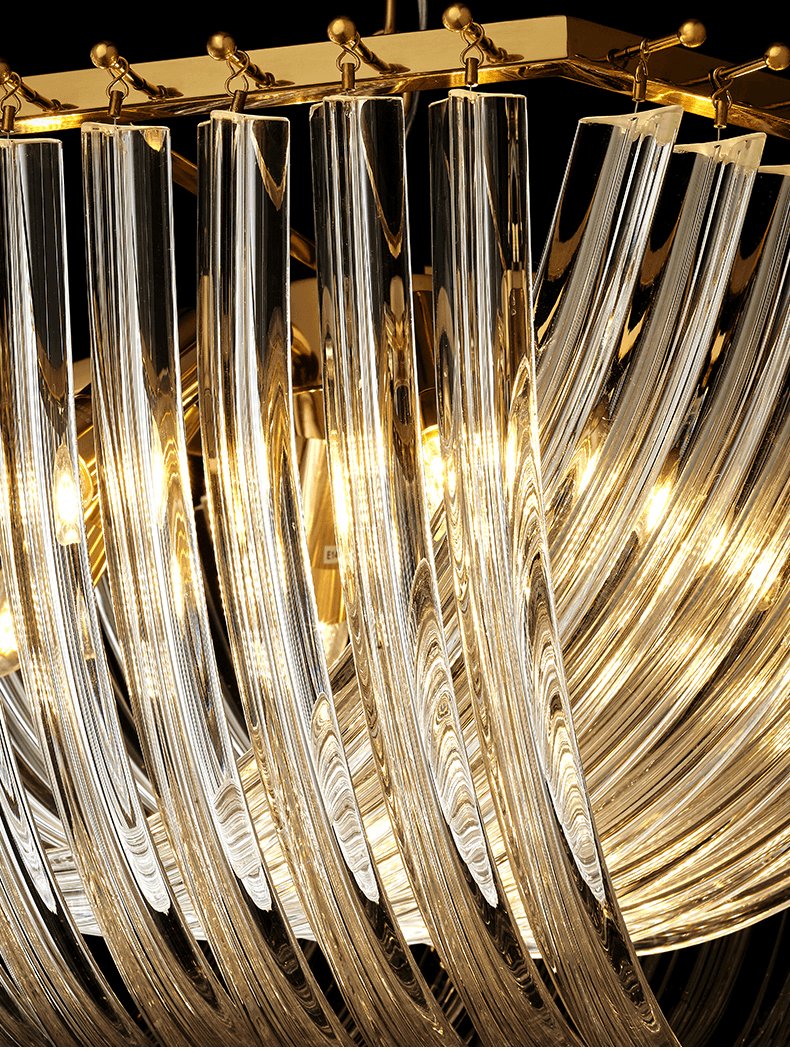 Close view of the clear glass rods and gold frame of this Clérachic chandelier, lit warmly from inside.