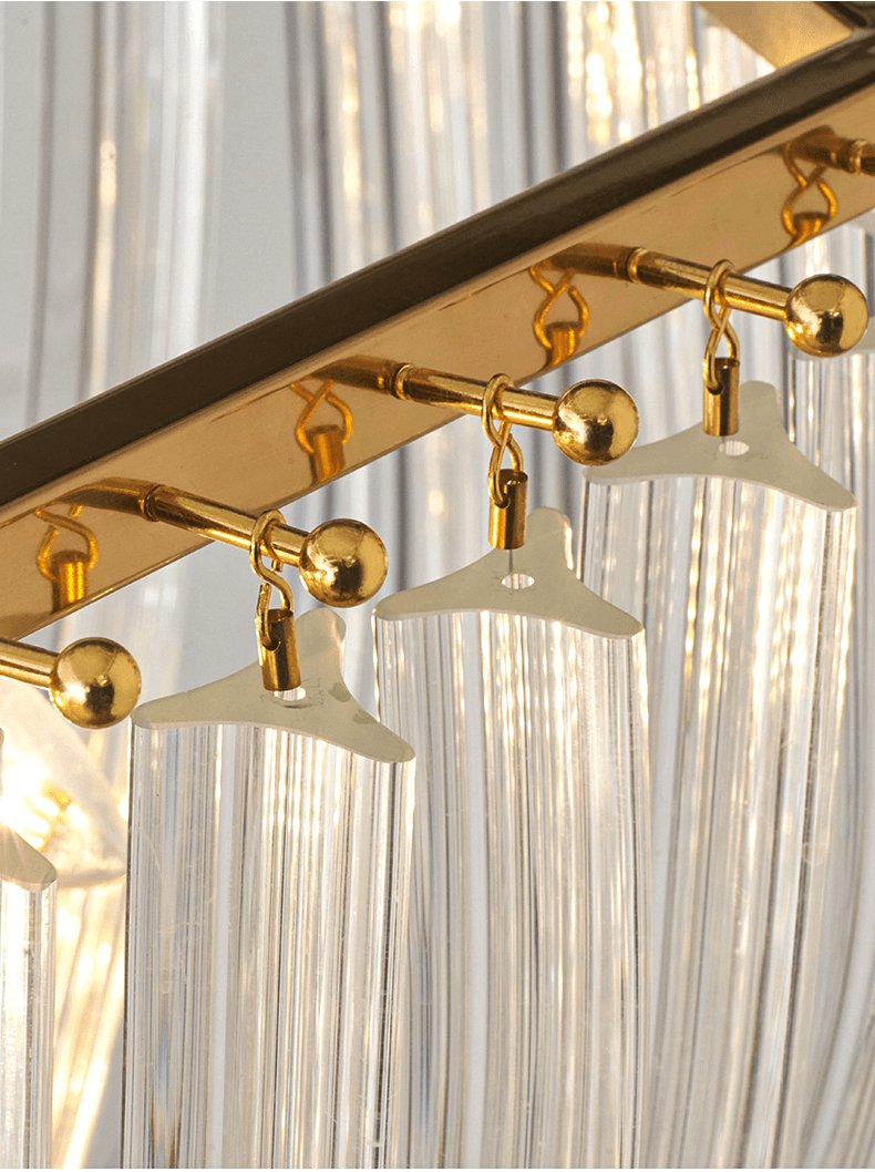 Close view of the gold rail and the small gold hooks with cream clips that hold the glass rods of this Clérachic chandelier.