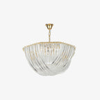 Slightly angled view of a Clérachic chandelier, with its curved clear glass rods and gold chain on a plain light backdrop.