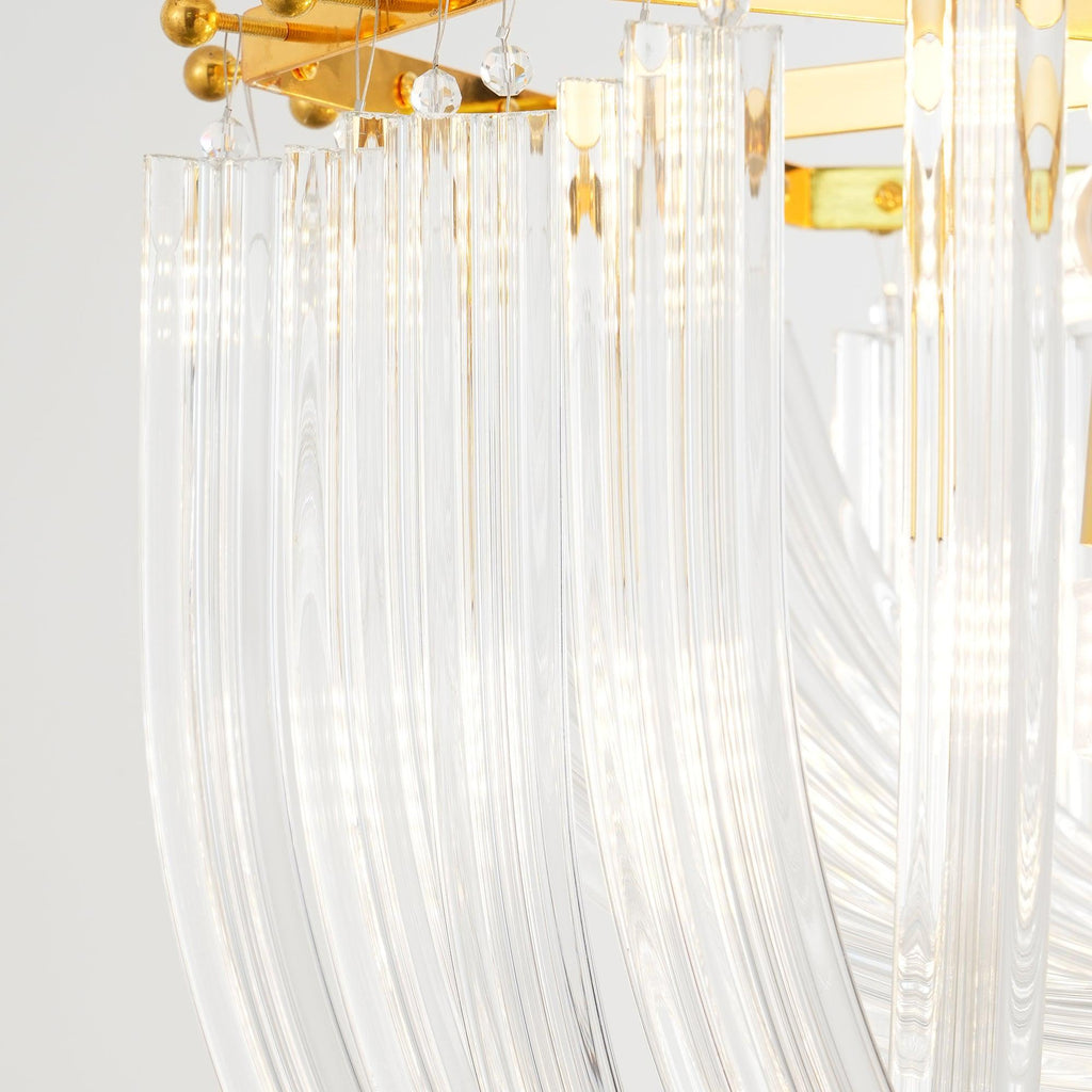Close view of curved clear glass rods hanging from the gold frame of this Clérachic chandelier on a pale backdrop.