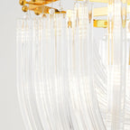 Close view of curved clear glass rods hanging from the gold frame of this Clérachic chandelier on a pale backdrop.