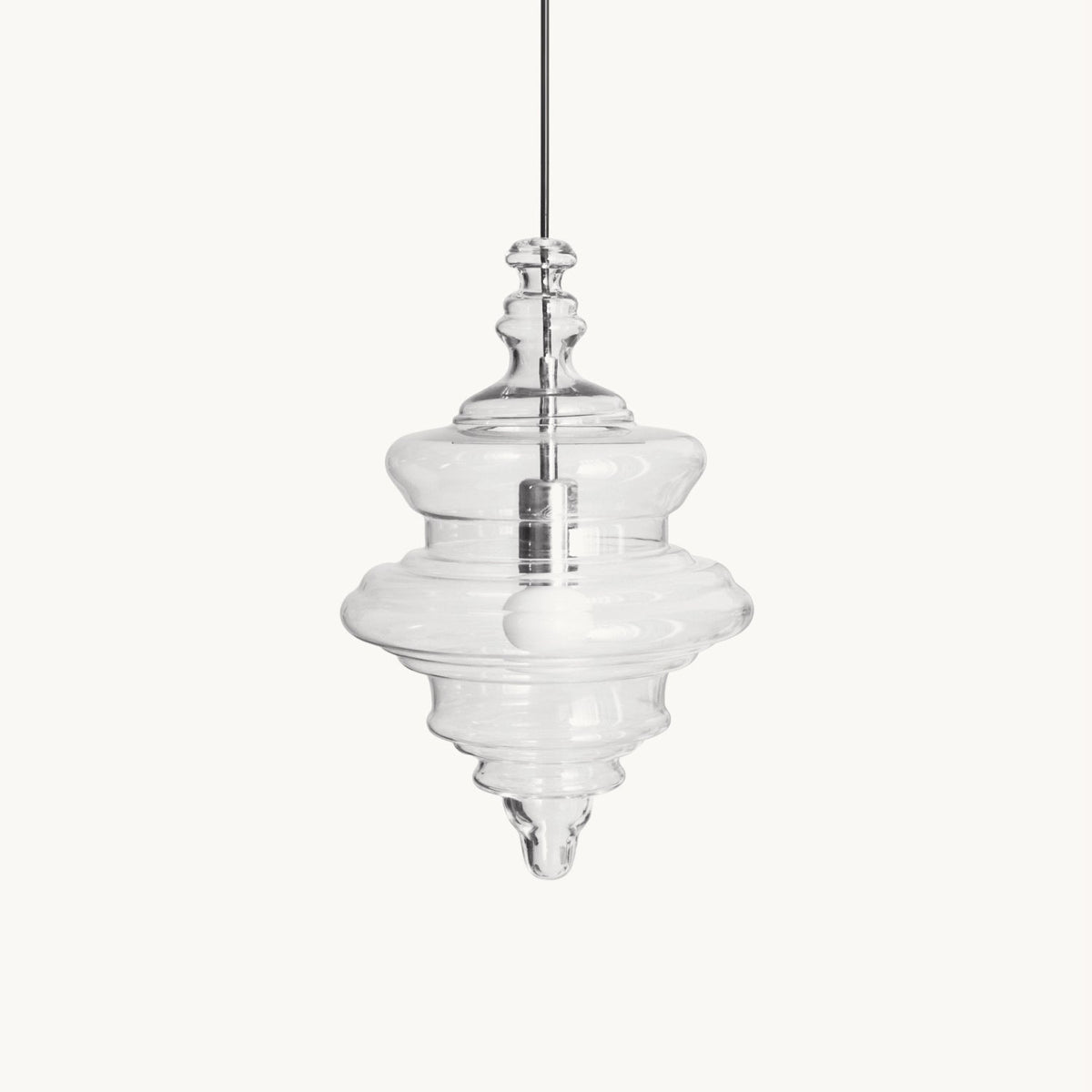 Clear glass pendant with stacked, tiered rings and a pointed tip hanging from a thin cord, on a plain white backdrop from Clérachic.