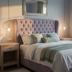 Two small clear glass Clérachic pendants glow on either side of a pink-purple tufted bed head, in place of bedside lamps.