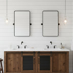 Clear glass pendants from Clérachic hang at both sides of a double vanity, beside two black-framed mirrors on a white boarded wall.
