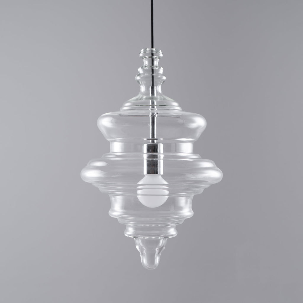 Tiered clear glass Clérachic pendant with a bulb inside, on a mid-grey backdrop with a black cord above.