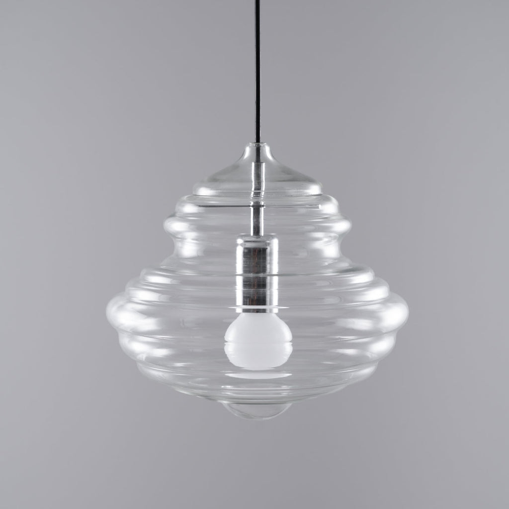 Wide, ribbed clear glass pendant from Clérachic with an unlit bulb and silver-toned holder, on a grey backdrop.