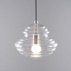 Ribbed Clérachic glass pendant lit warm, on a plain grey backdrop, with horizontal rings running down the shade.