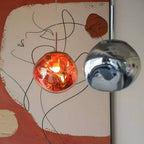 Close view of a copper-red and a smoke-grey Clérachic glass pendant in front of a painted wall with a line drawing.