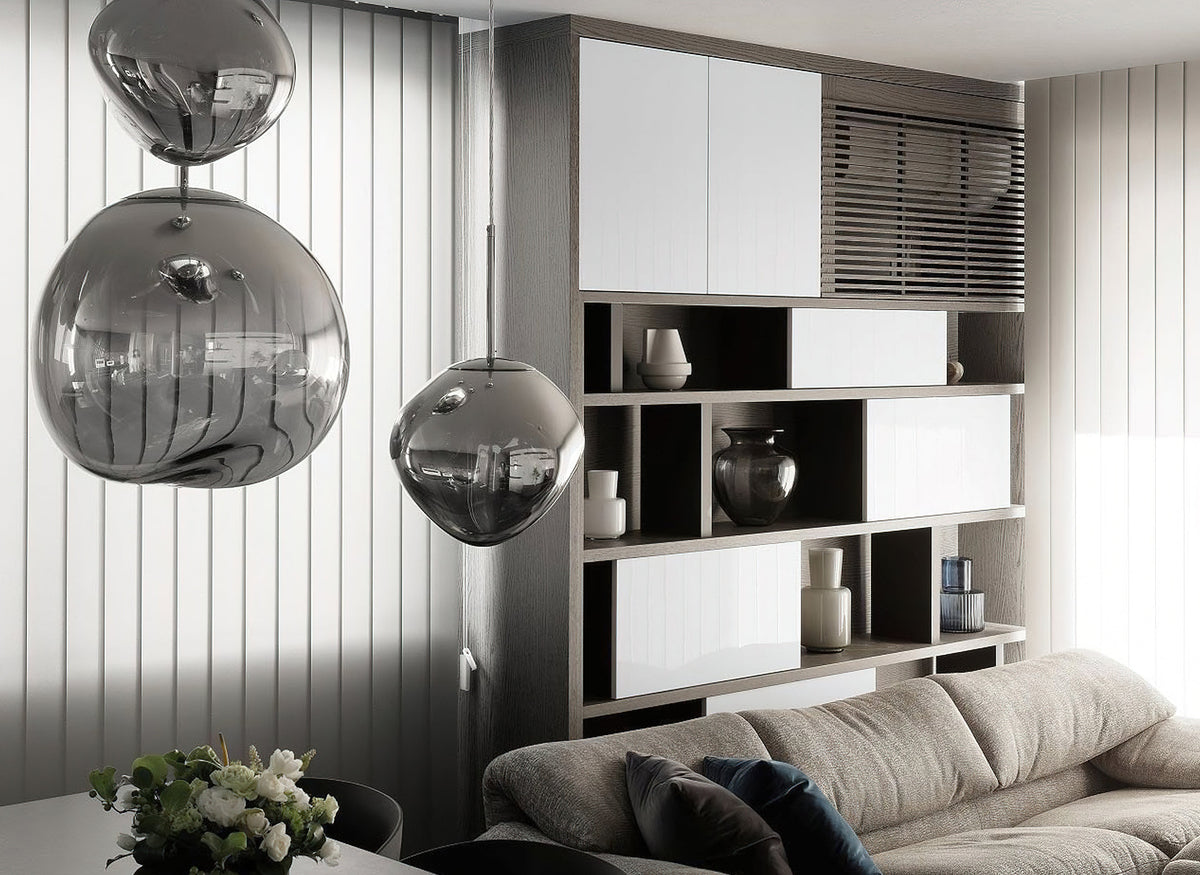 Two Clérachic silver glass pendants hang beside a glossy white cabinet and shelving, above a sofa and a bunch of white flowers.