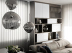 Two Clérachic silver glass pendants hanging in a room with white panelling, with a grey sofa and a vase of flowers below.