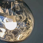 A Clérachic silver glass pendant seen up close, with a frosted bulb and swirling reflections across the glass.
