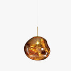 A Clérachic gold glass pendant on a light backdrop, with a brass rod, a rounded irregular shade and a bright bulb.