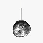 A Clérachic silver glass pendant on a pale backdrop, with a long polished rod and bright swirls across its surface.