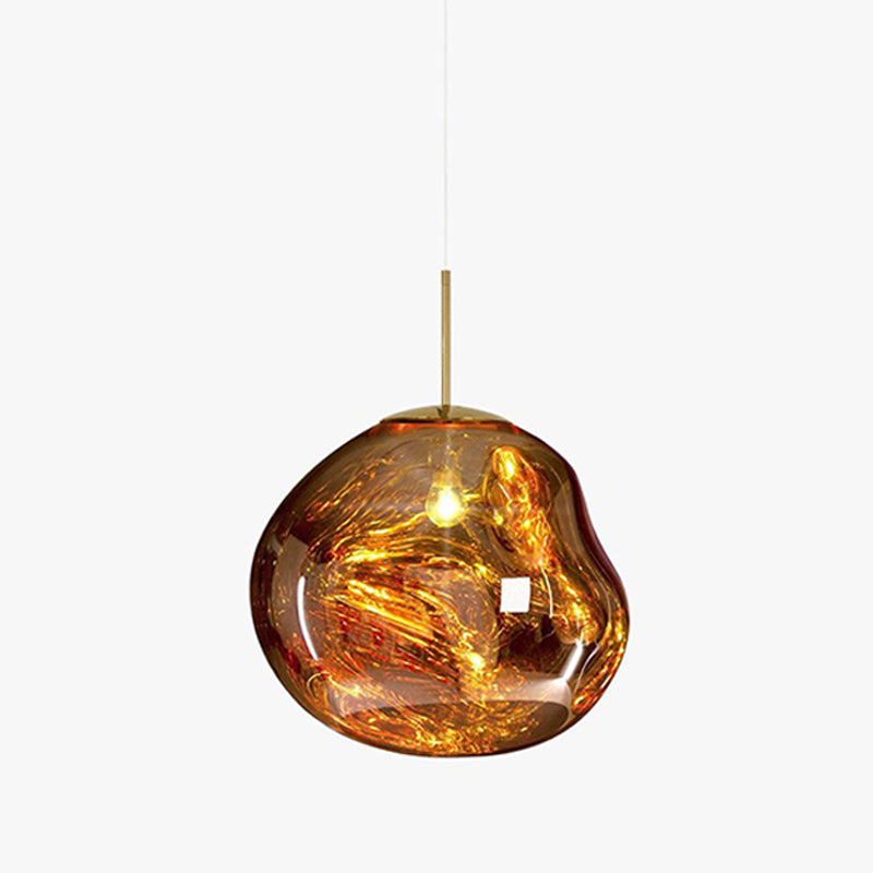 A Clérachic gold glass pendant on a pale backdrop, with a slim brass rod and a molten-looking shade with a lit bulb.