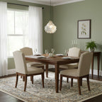 A single Clérachic shell pendant hangs above a dark wood dining table with cream chairs, in a sage-green room with sheer curtains.