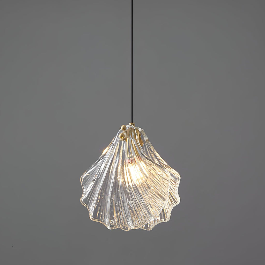 Clérachic ribbed shell pendant in clear glass with an amber edge, lit and hanging from a black cord against grey.