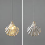 Side-by-side views of a Clérachic shell pendant on grey, one lit with an amber rim and one unlit and plain clear.
