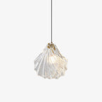 A Clérachic shell pendant with layered clear glass ribs, lit and hanging from a thin black cord on a white background.