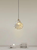 A Clérachic shell pendant hangs high in a pale, minimal room, with a small sofa and a low round table far below.