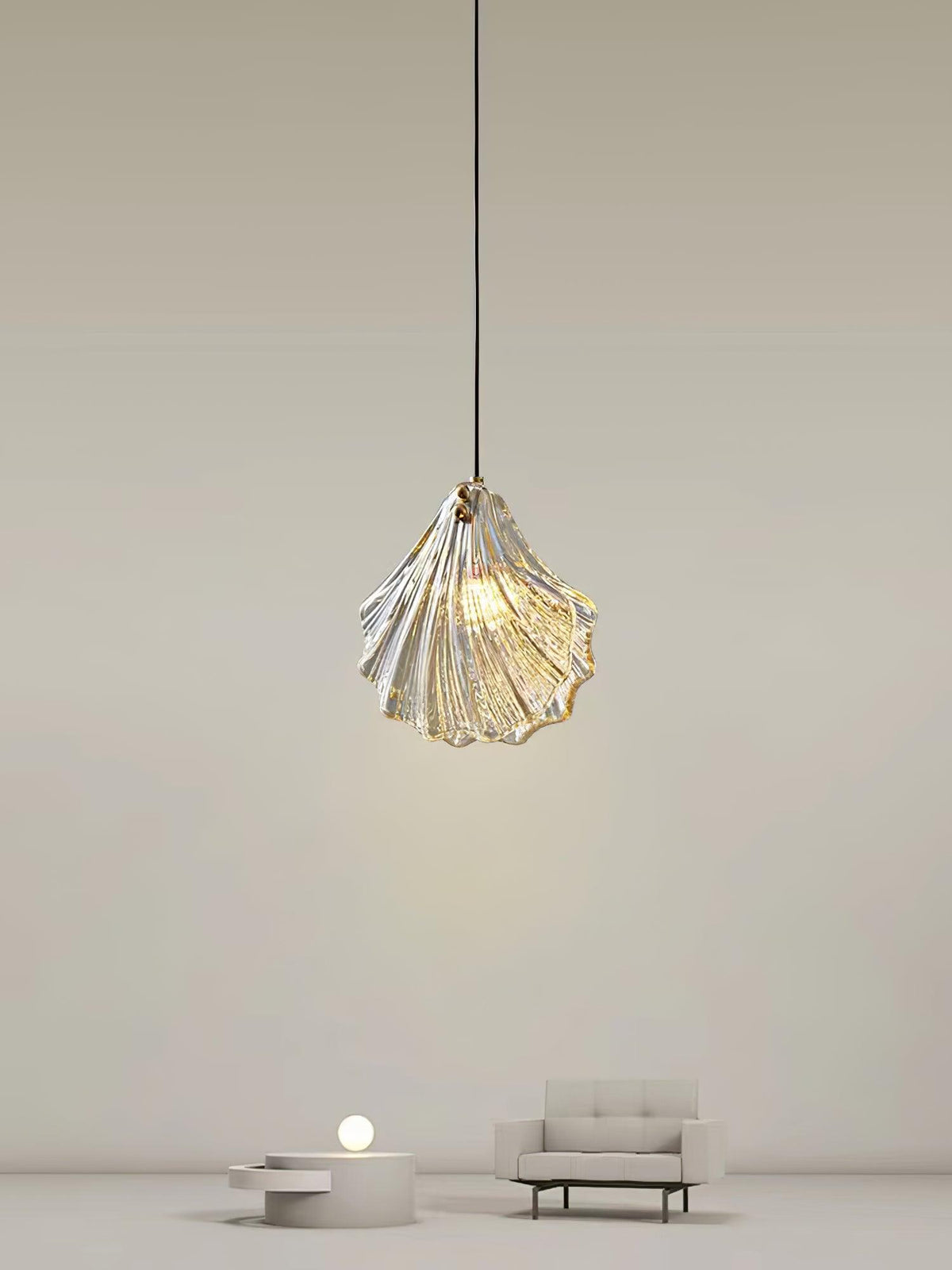 A Clérachic shell pendant hangs high in a pale, minimal room, with a small sofa and a low round table far below.