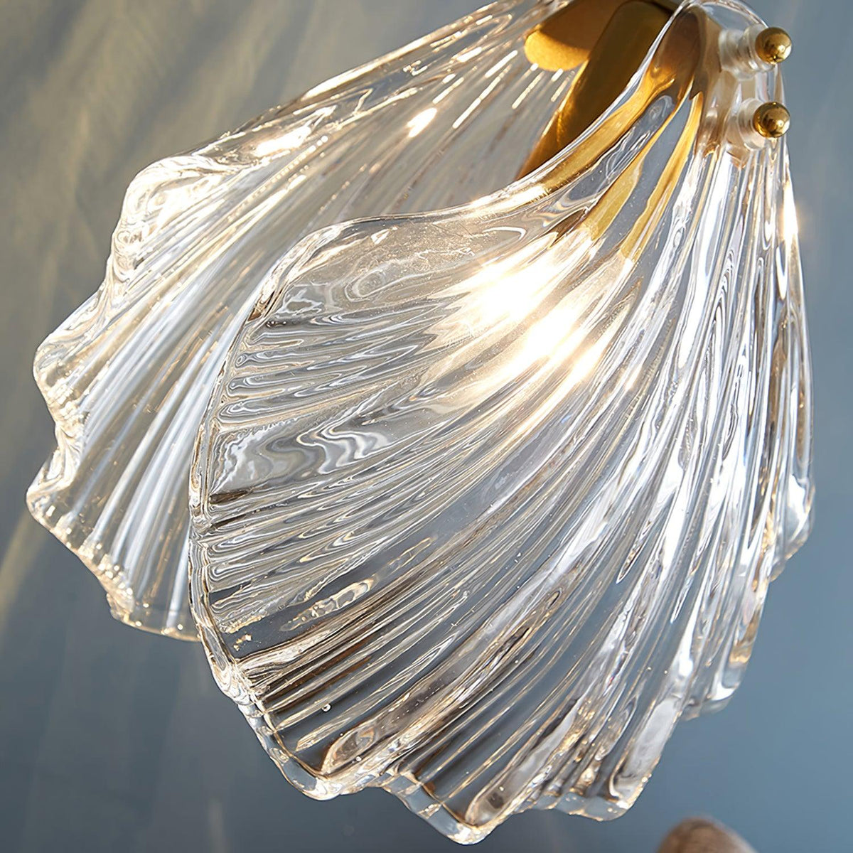 Close view of the layered, ribbed glass of this Clérachic shell pendant, lit from inside with a brass fitting at the top.