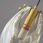 Close view of the brass lamp holder and small brass knobs on this Clérachic shell pendant, with the LED bulb inside the glass.