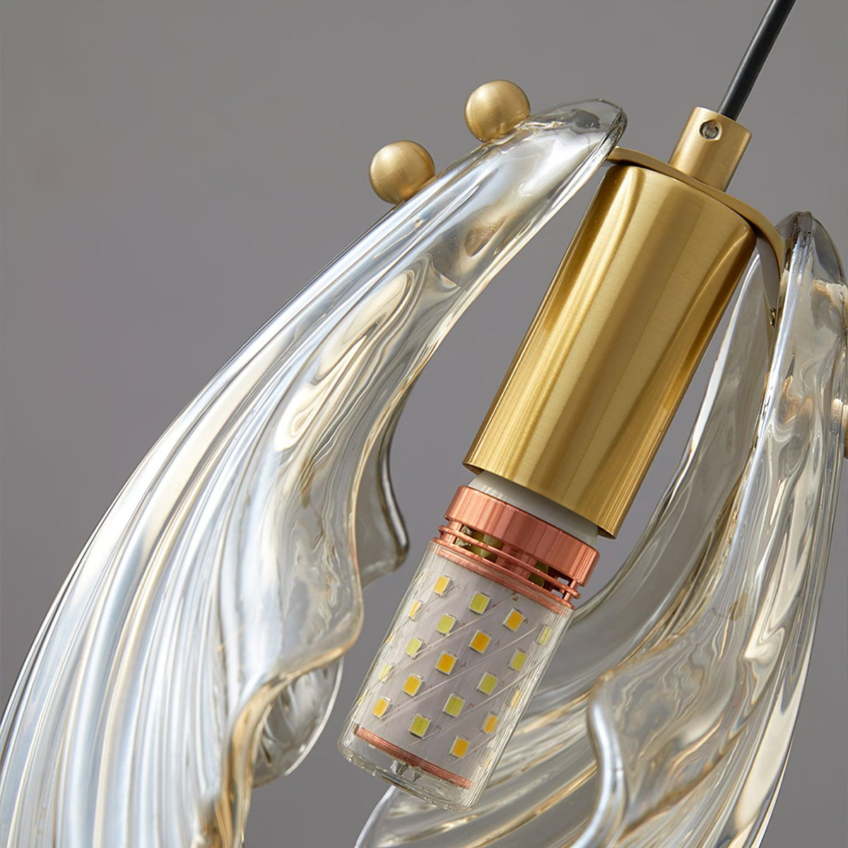 Close view of the brass lamp holder and small brass knobs on this Clérachic shell pendant, with the LED bulb inside the glass.