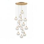 A tall Clérachic cluster of clear glass shell pendants on thin cords, hung at staggered heights from a round brass plate.