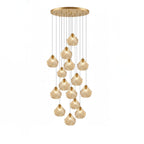 A long Clérachic cluster of cognac glass shell pendants hangs at staggered heights from a round brass ceiling plate.