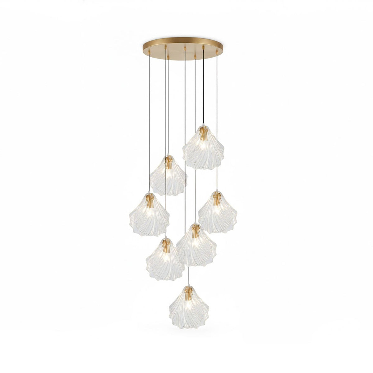 A Clérachic cluster of seven clear glass shell pendants hangs at staggered lengths from a round brass plate, on white.