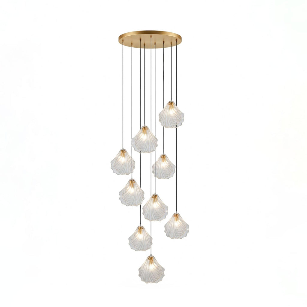 A Clérachic cluster of nine clear glass shell pendants hangs at different lengths from a round brass ceiling plate.