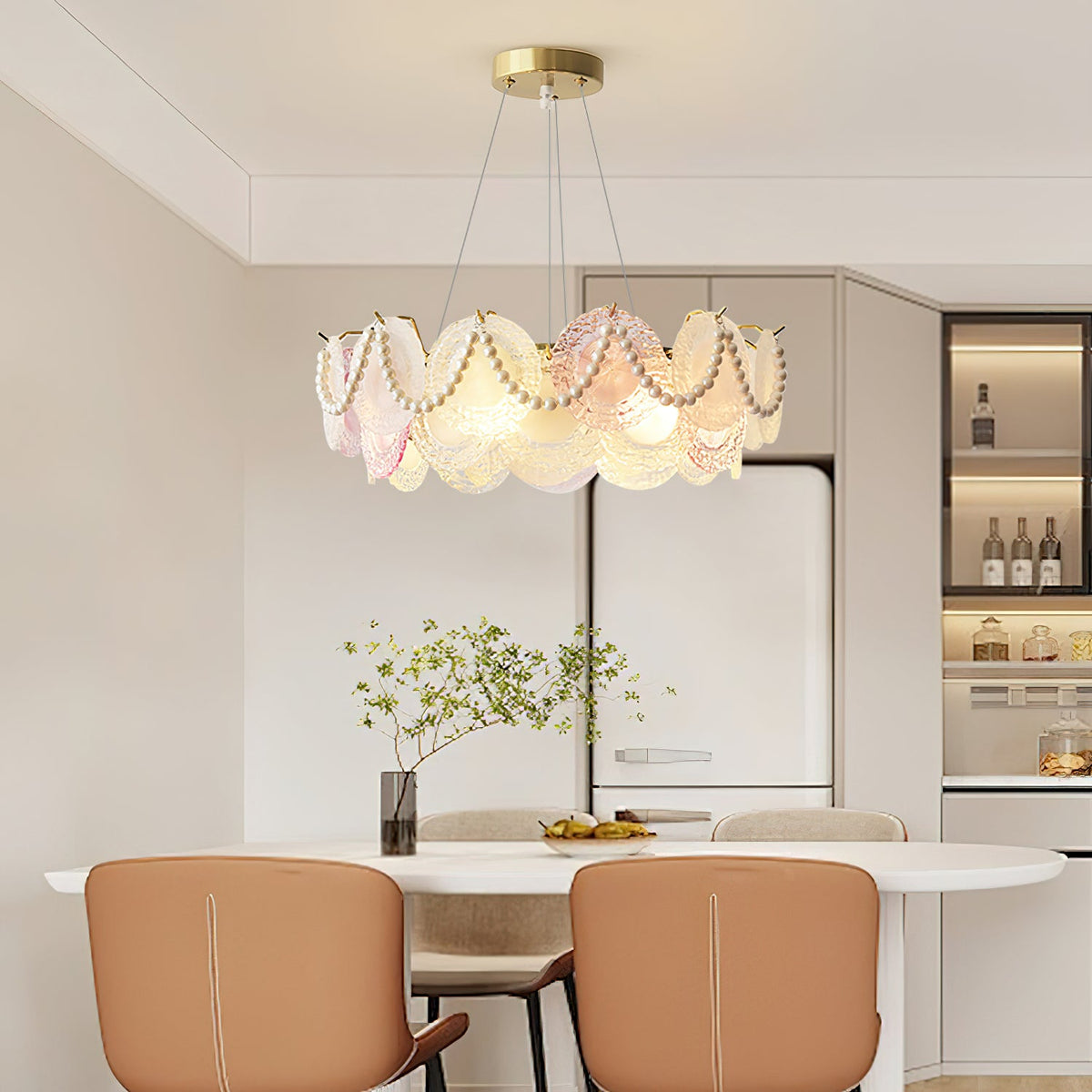 This Clérachic pendant with pearl swags across its glass discs hangs over a white oval dining table with tan leather chairs.