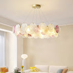 A Clérachic ring pendant of pink and frosted glass discs, lit, hung high in an open living room with a cream sofa behind it.