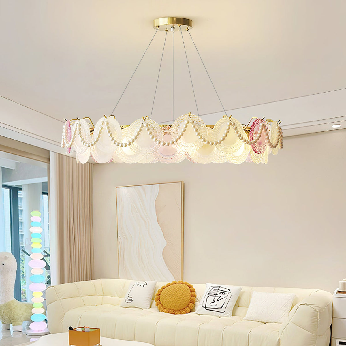 Clérachic pendant with pearl swags and glass discs, lit, hung in a living room above a cream sofa with a yellow cushion.