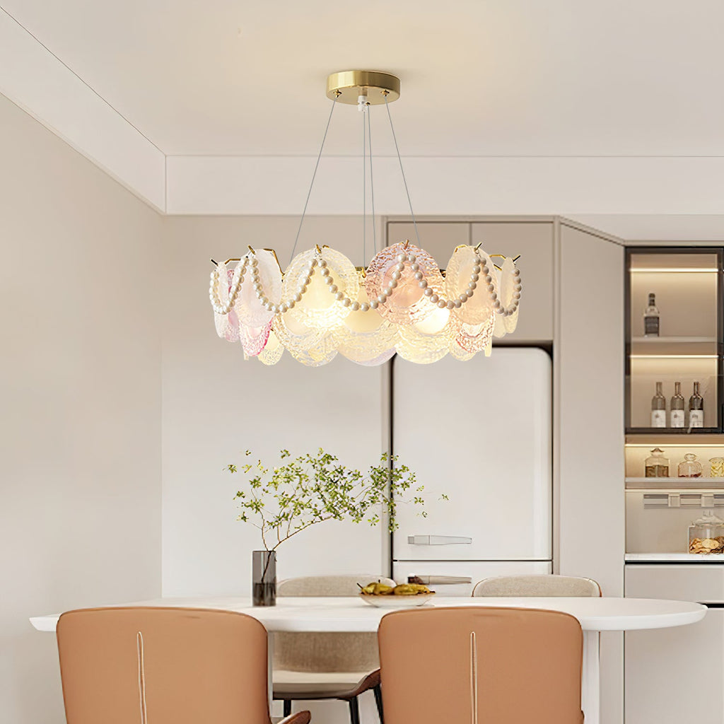 A Clérachic pearl-swagged glass-disc pendant in a bright dining area, with a white table and tan chairs under it.