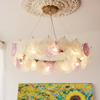 This Clérachic pendant hangs from an ornate plaster ceiling rose, with two rows of pink and frosted glass discs and a sunflower painting below.
