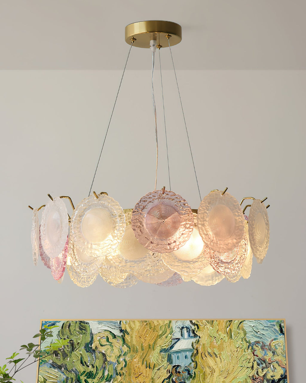 Clérachic round pendant of pink and frosted discs on thin wires, with a bright green landscape painting just below it.